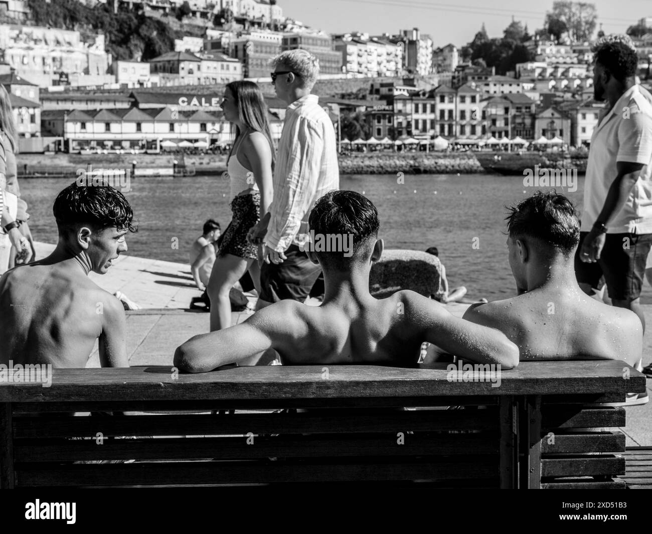 Vue arrière de trois adolescents assis sur un banc pendant les températures élevées de la vague de chaleur au Riverside 29.05.2024 de Porto Banque D'Images