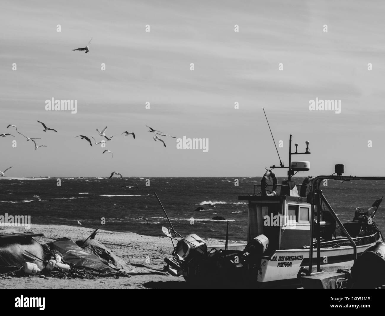 Vieux bateaux de pêche noir et blanc dans le sable sur l'océan au Portugal sur le ciel bleu et mouettes sur un fond. Praia de Angeiras.Portugal.26.05.2024 Banque D'Images