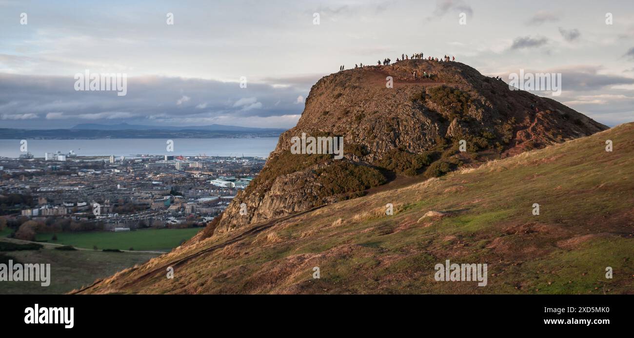 Vue sur le sommet de la colline Arthur Seat à Édimbourg avec des gens au sommet et la ville et le Firth of Forth en arrière-plan Banque D'Images