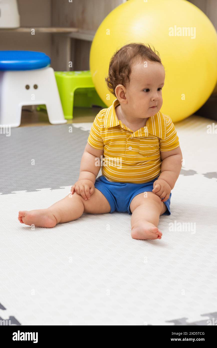 Jeune enfant garçon est assis sur un tapis pendant une séance de physiothérapie. Banque D'Images