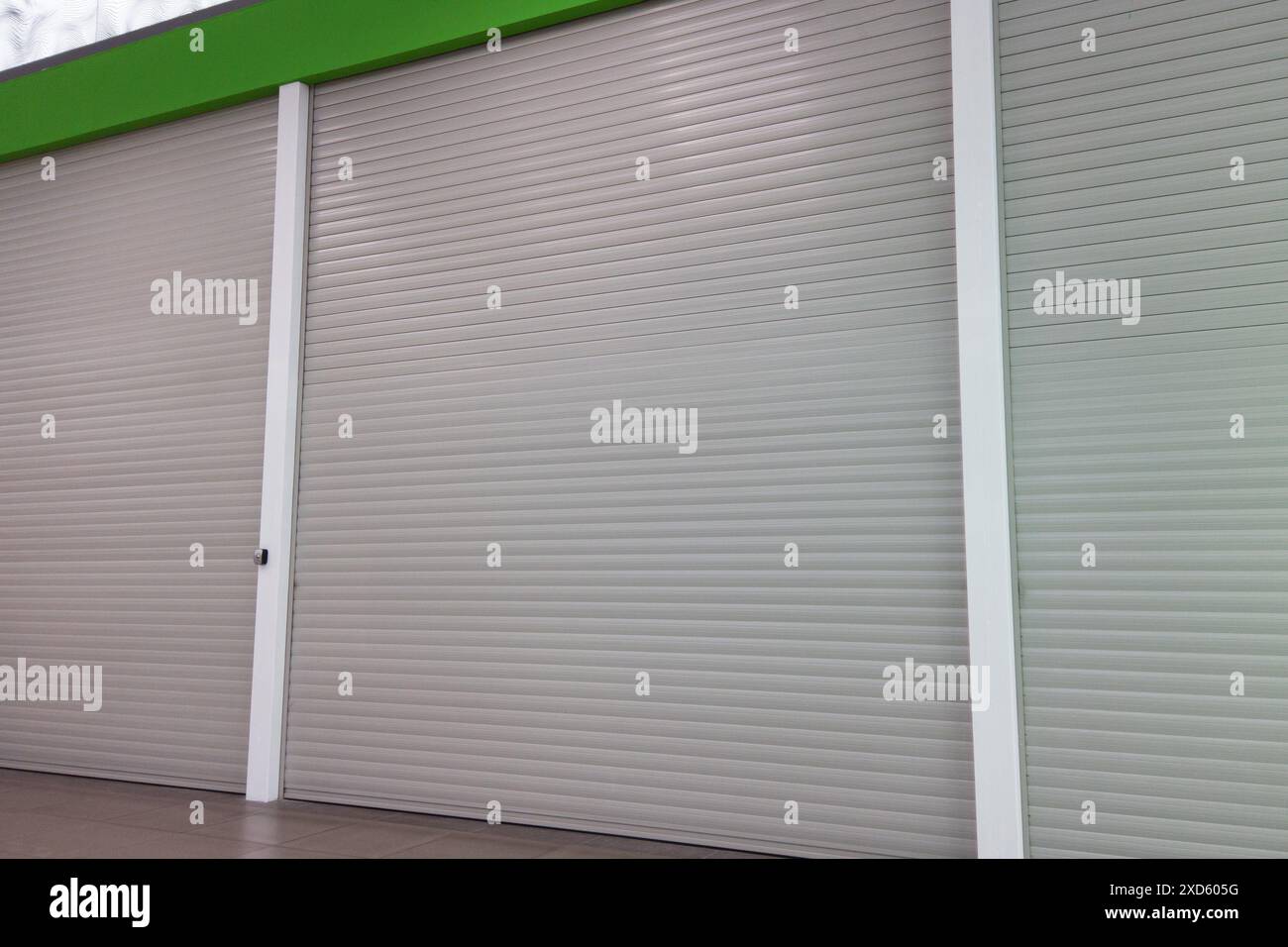 Volets roulants en métal gris fermés sur un bâtiment moderne avec un accent vert Banque D'Images