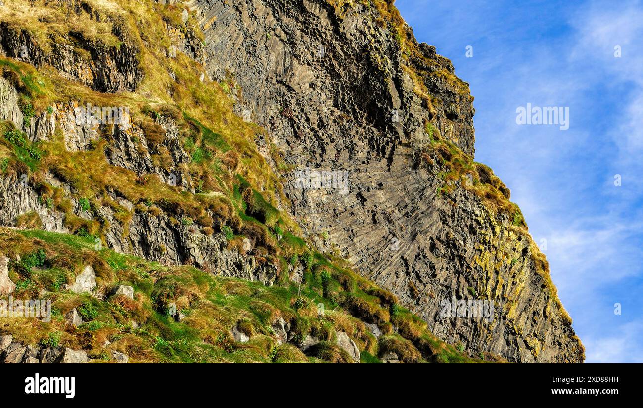 Une colline rocheuse avec quelques plantes poussant dessus. Le ciel est clair et bleu Banque D'Images