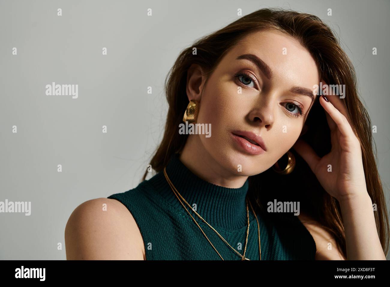 Une femme dans un sommet vert tient sa main à son oreille, comme si elle écoutait attentivement Banque D'Images
