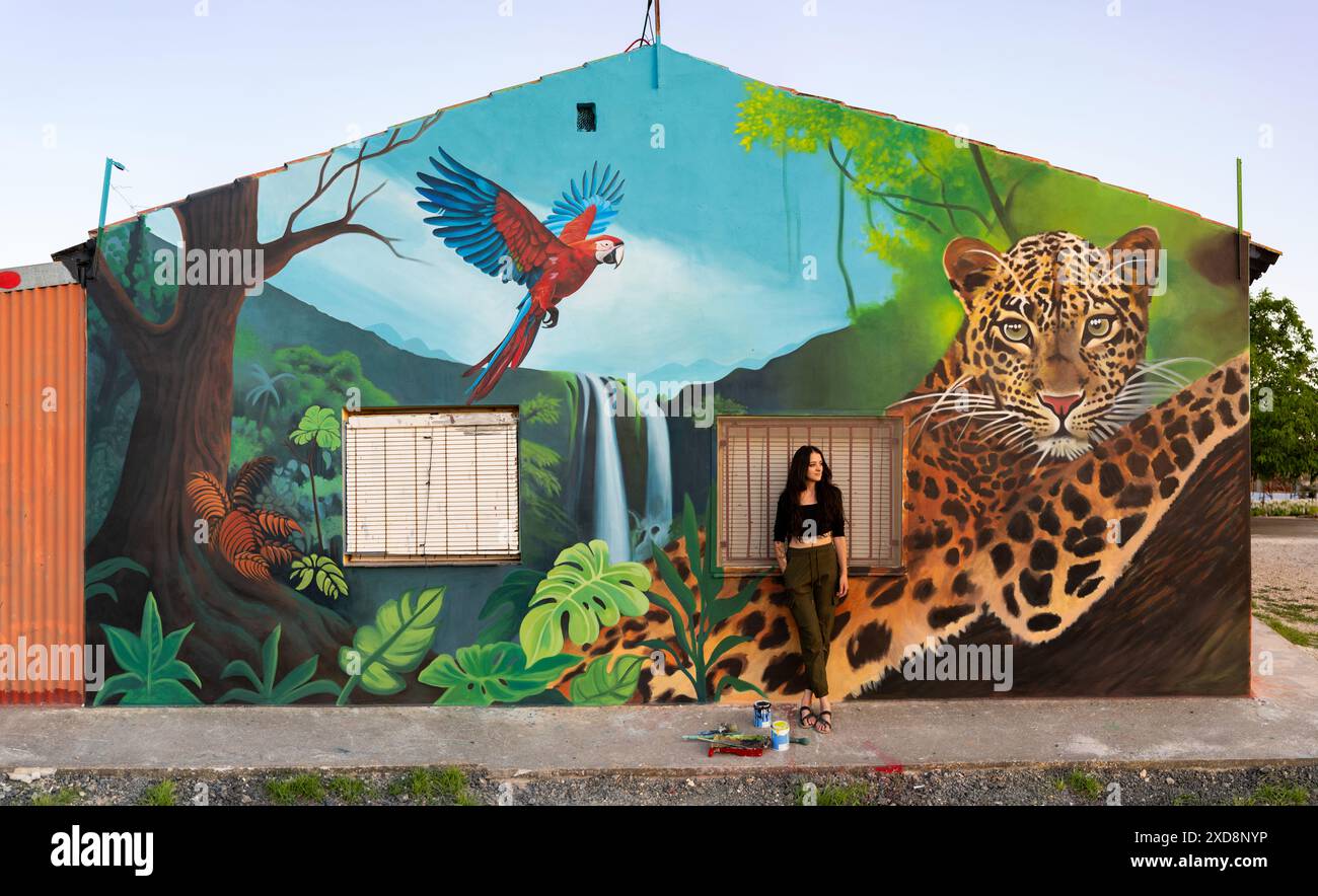 Femme posant devant une murale de la jungle représentant un léopard et un aras Banque D'Images