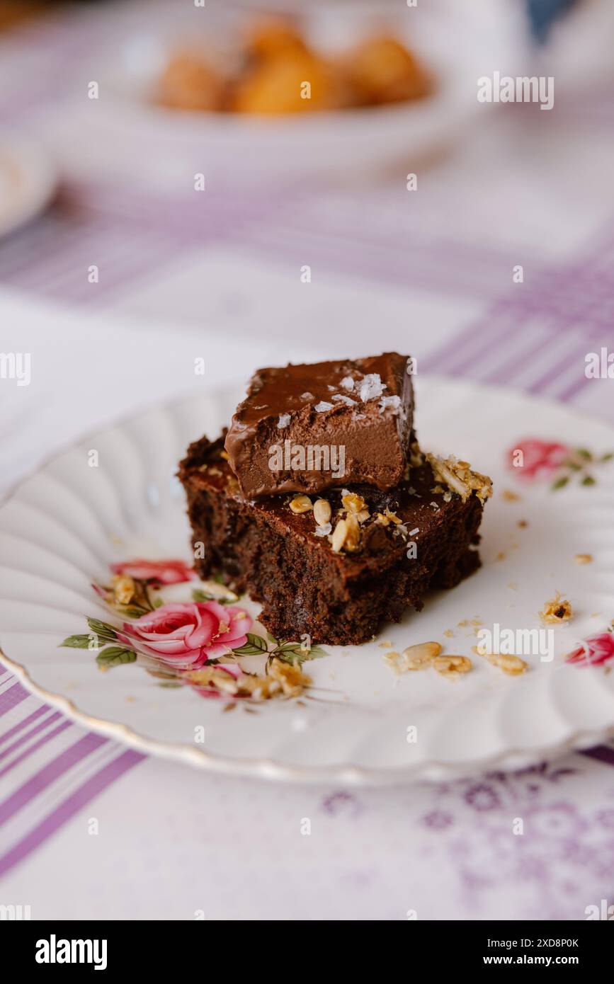 Brownie au chocolat garni de ganache et de sel de mer sur une assiette florale. Banque D'Images