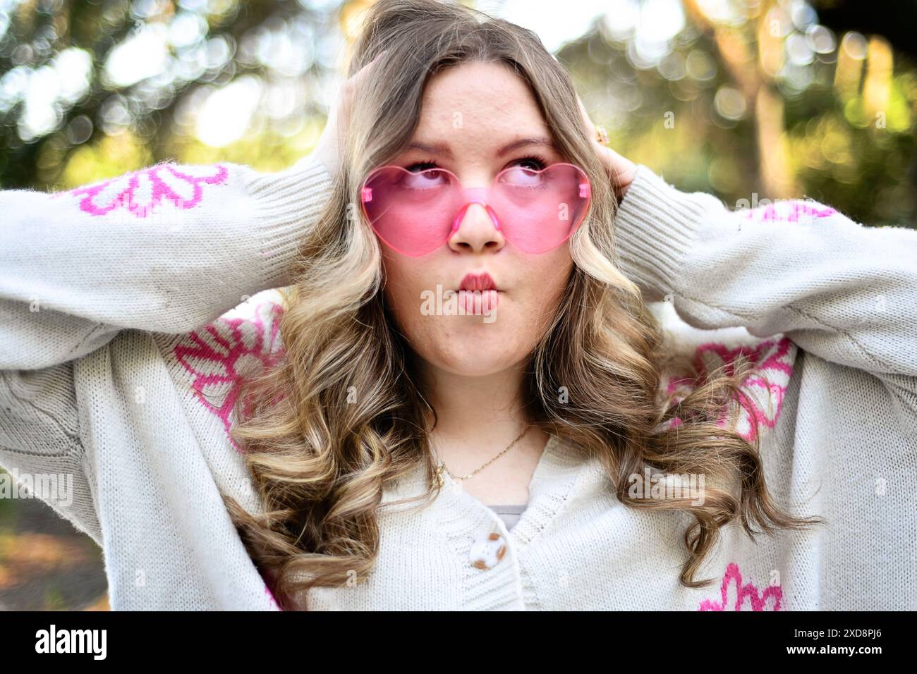 Fun, femme aux cheveux blonds fait un visage ludique, portant le coeur- Banque D'Images