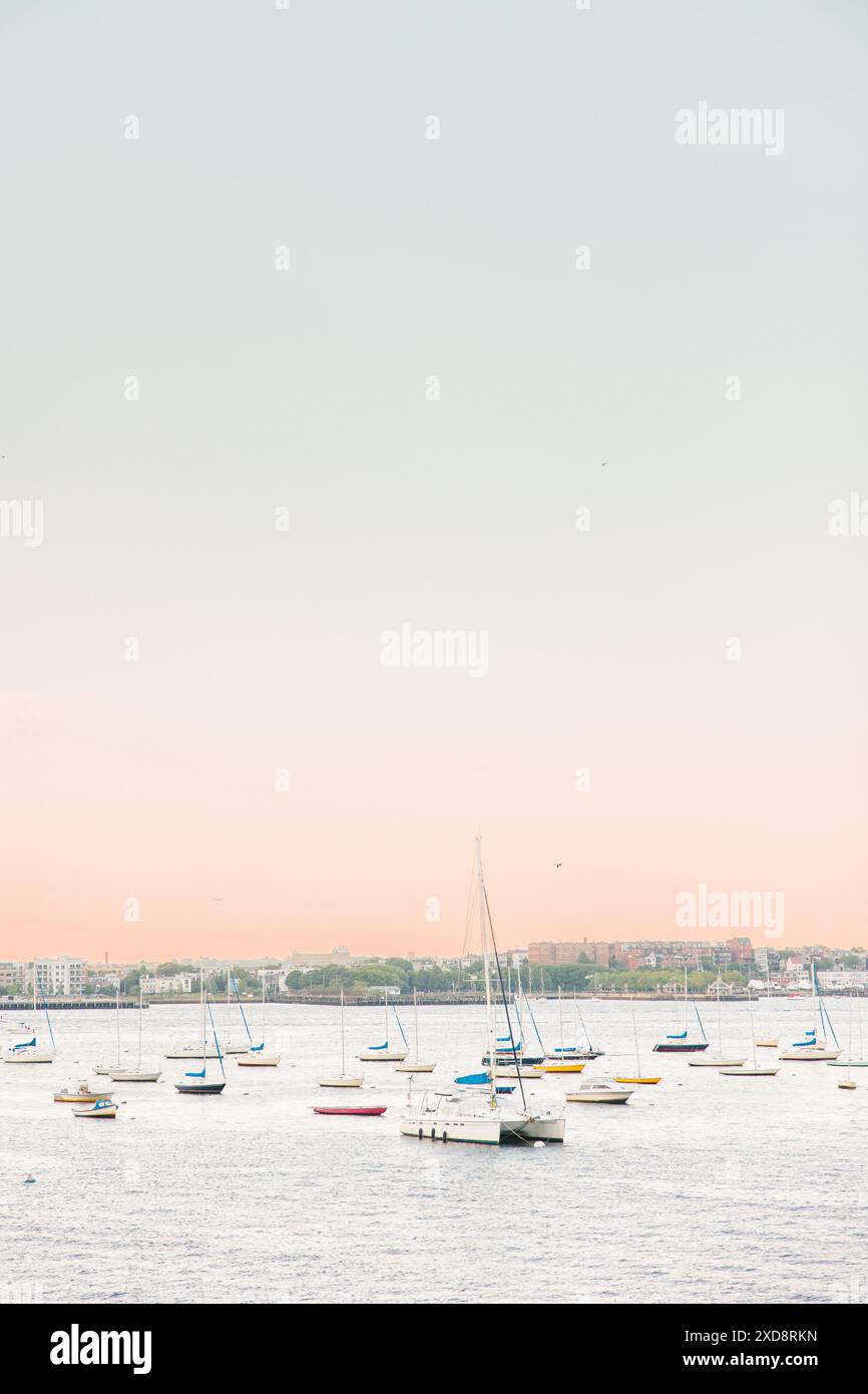 Bateaux ancrés dans un port calme au coucher du soleil avec un ciel pastel Banque D'Images