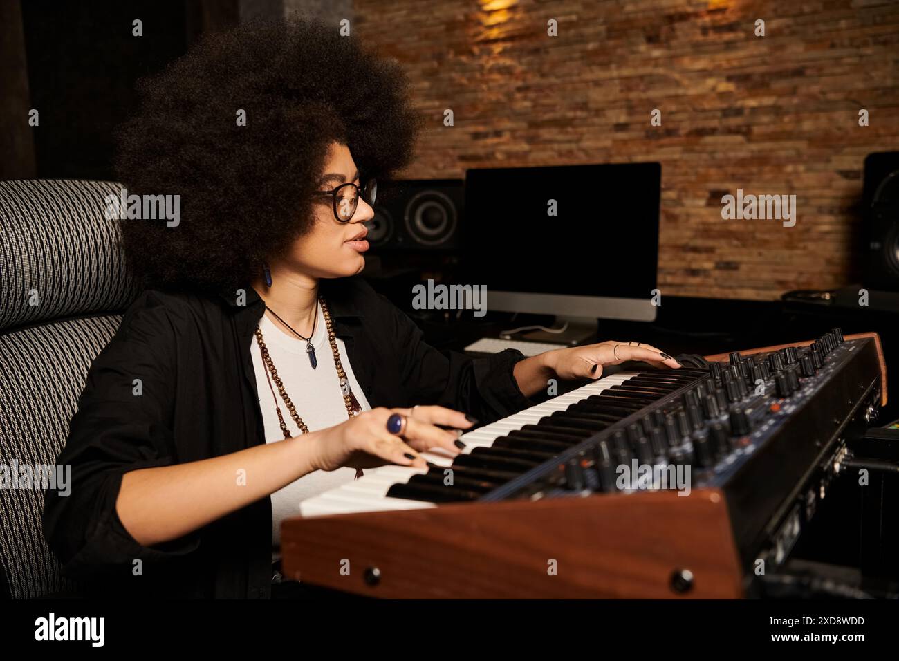 Une femme talentueuse joue du clavier dans un studio d'enregistrement lors d'une répétition d'un groupe de musique. Banque D'Images