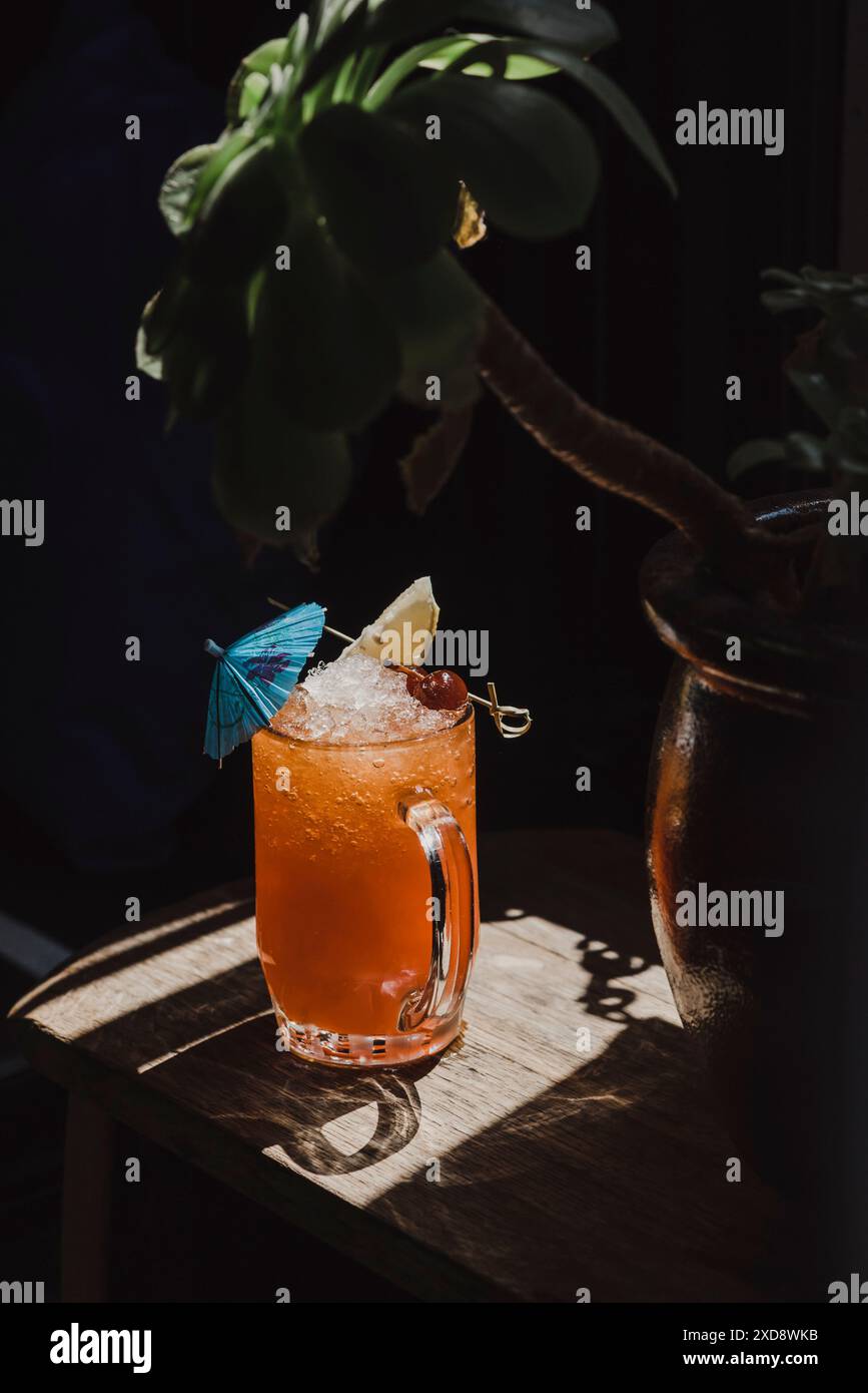 Cocktail tropical rafraîchissant avec de la glace de galets dans un éclairage tamisé Banque D'Images