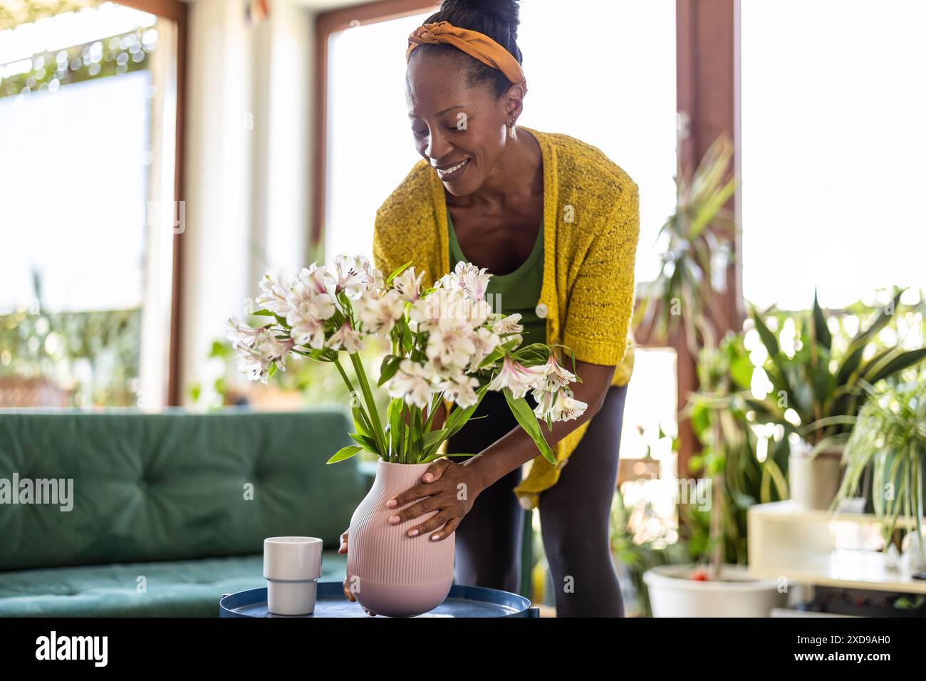 Portrait de femme souriante tenant vase avec des fleurs à la maison Banque D'Images