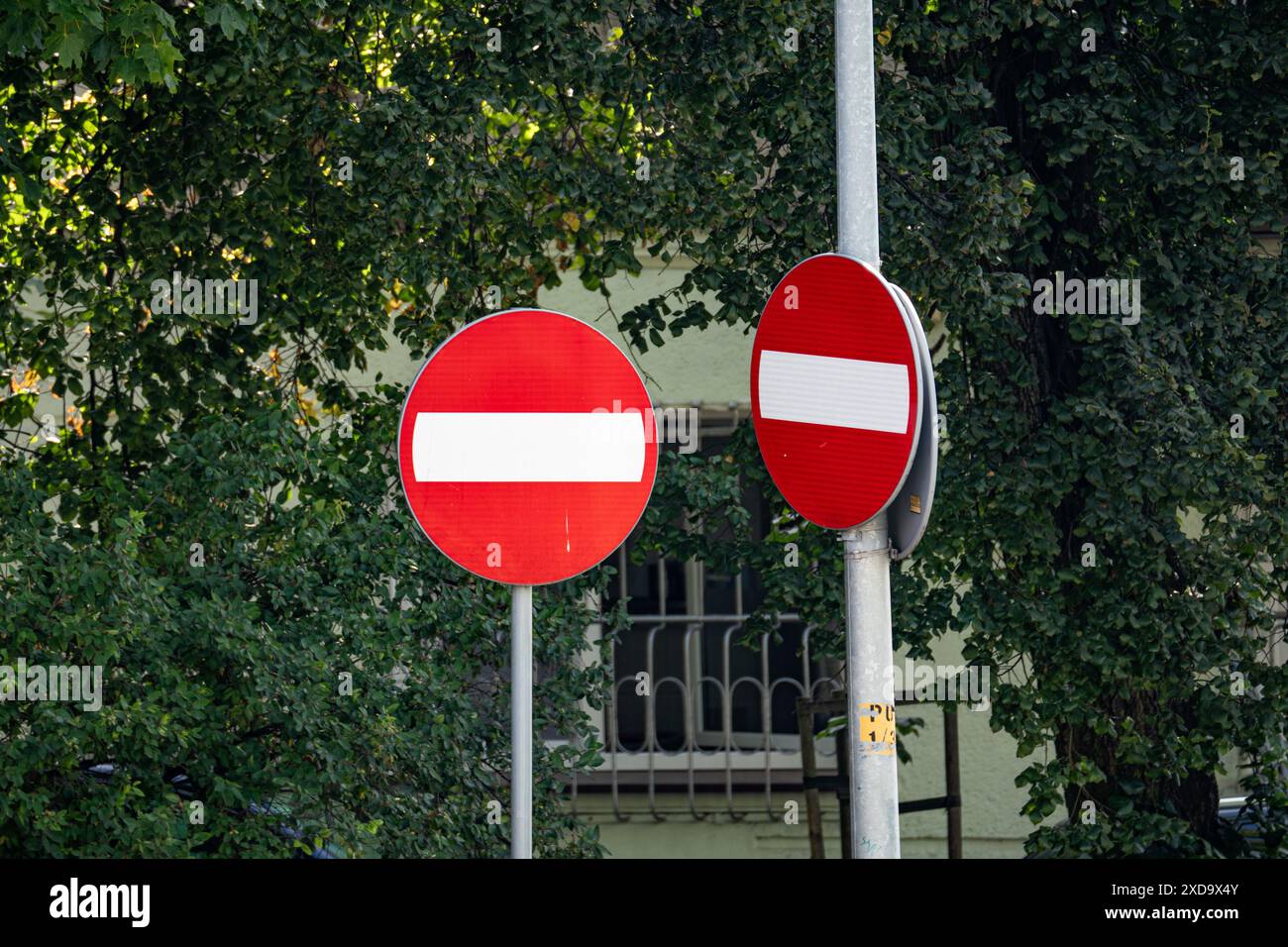 Deux panneaux rouges interdisant l'entrée sur un poteau devant Green Trees Banque D'Images