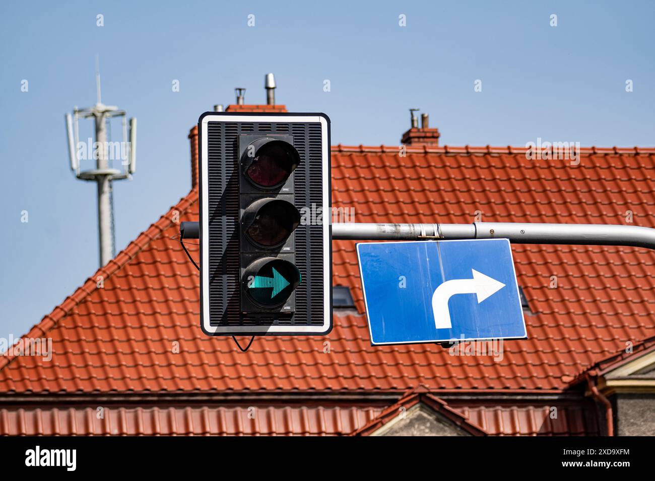 Feu de signalisation avec flèche verte et panneau de virage à droite sur Un toit Banque D'Images