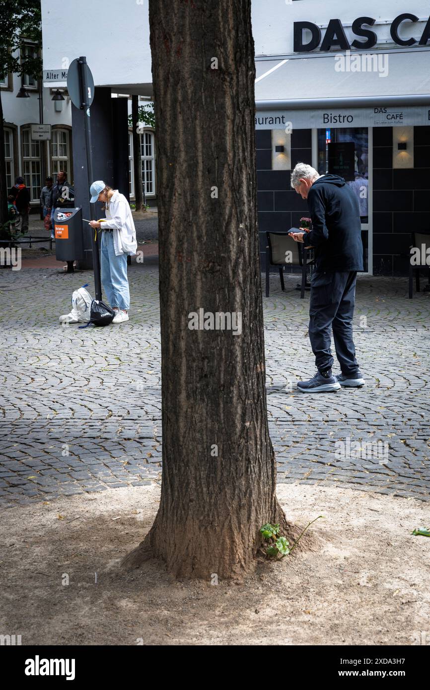 Une jeune femme et un homme plus âgé se tiennent sur Alter Markt regardant leurs téléphones portables, Cologne, Allemagne. ###USAGE ÉDITORIAL UNIQUEMENT## eine Junge Frau und ein Banque D'Images