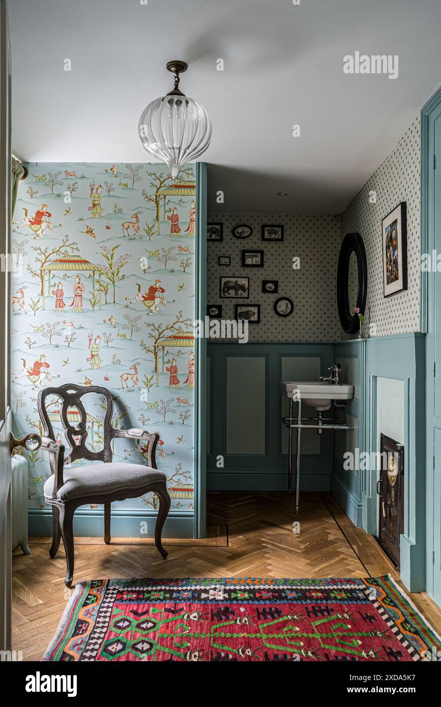 Chaise antique avec papier peint oriental dans la salle de bains de maison de campagne du 16ème siècle, Suffolk, Angleterre, Royaume-Uni Banque D'Images