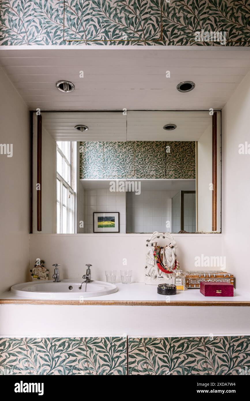 Évier encastré et miroir avec papier peint William Morris 'Willow Boughs'. Terrasse victorienne classée grade II, Camden, Londres, Royaume-Uni Banque D'Images