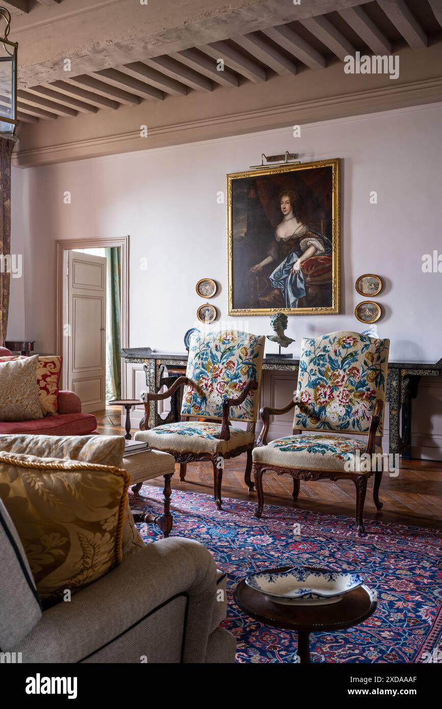 Paire de chaises anciennes couvertes avec des œuvres d'art dorées encadrées sous poutres apparentes dans un hôtel particulier en pierre rénové datant de 1770 à Saulieu, B. Banque D'Images