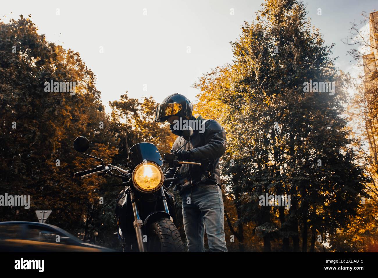 Motocycliste dans un casque et des vêtements de moto se tient à un vieux coureur de café Banque D'Images