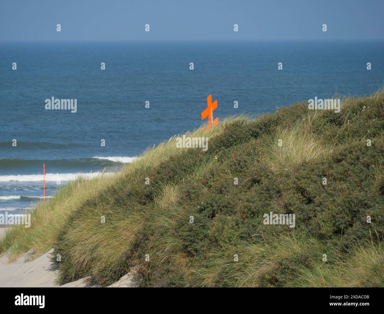 Dunes herbeuses avec vue sur la mer et les vagues, une croix orange au premier plan, Juist, Frise orientale, Allemagne Banque D'Images