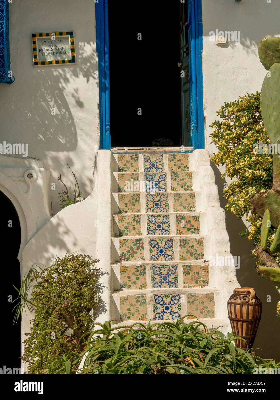 Escalier en carrelage blanc mène à une porte bleue entourée de plantes vertes, Tunis, Tunisie Banque D'Images