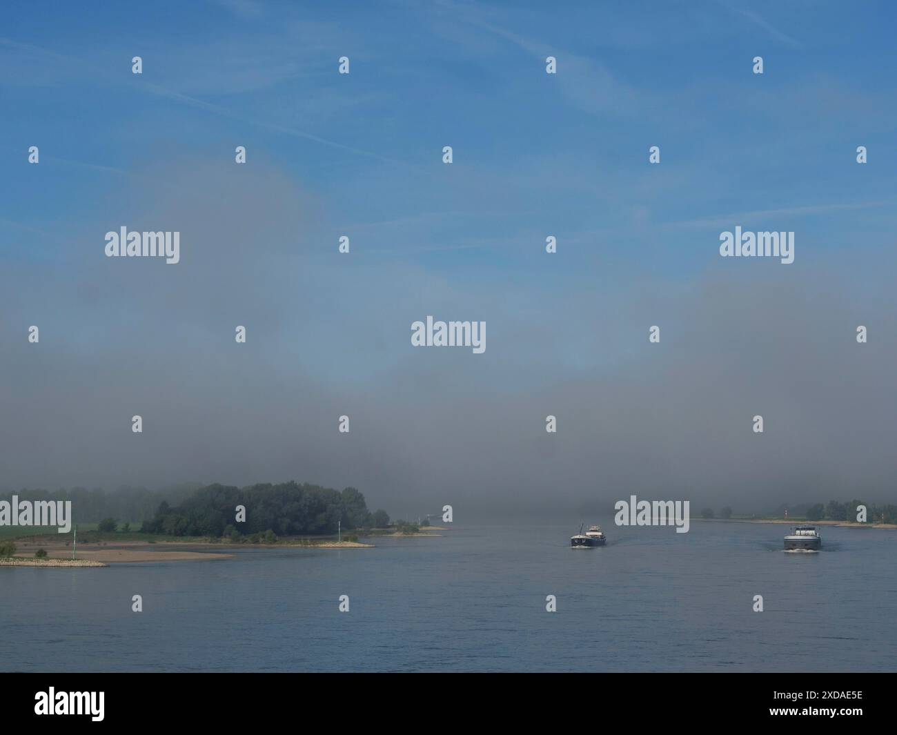 Deux bateaux sur une rivière brumeuse sous un ciel bleu, rive visible, wesel, rhin, allemagne Banque D'Images