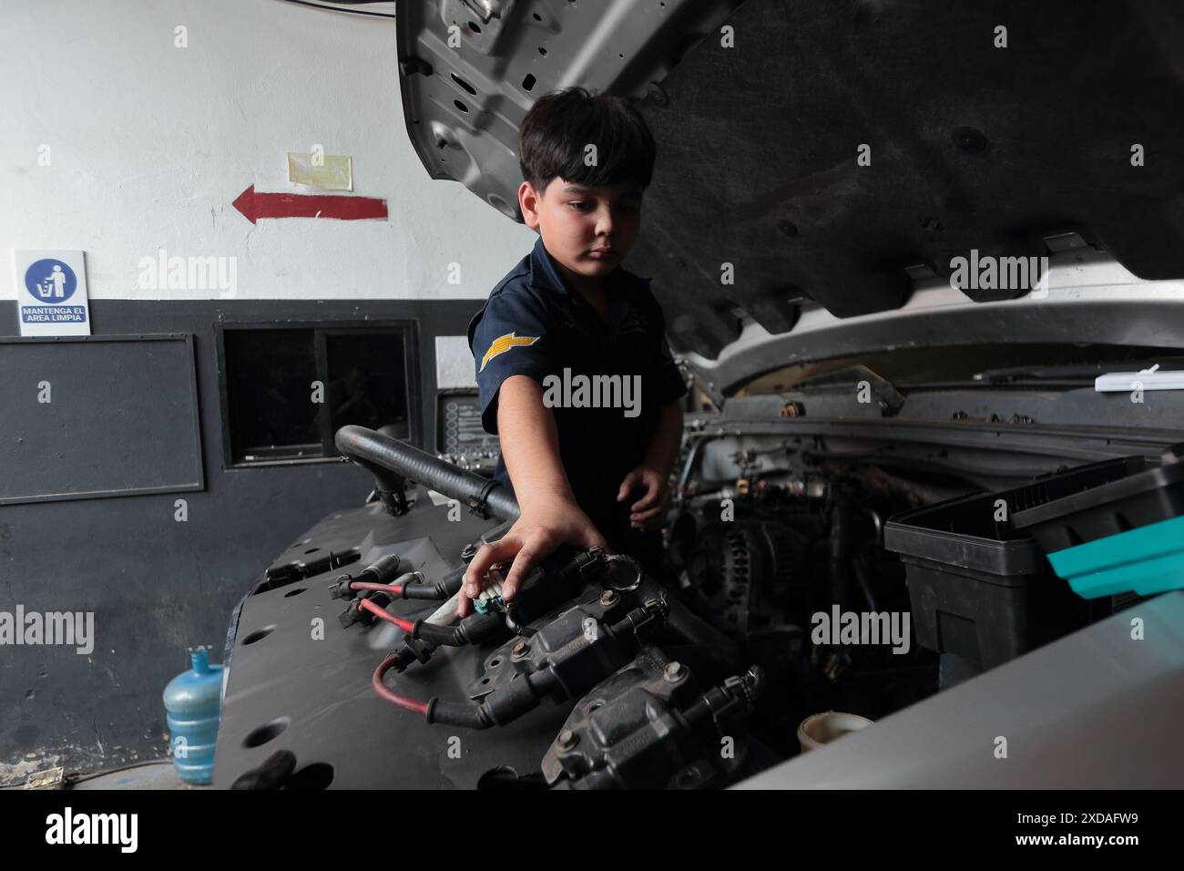 Maracaibo, Venezuela.5-14-2024. Alejandro Matias arrive à l’atelier de son père après l’école pour aider son père comme mécanicien. Photo de. Jose I. Bula Banque D'Images