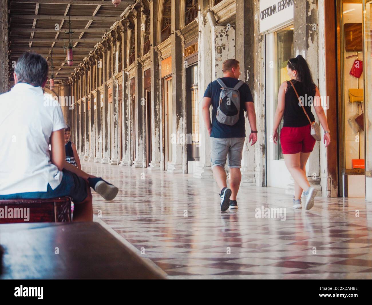 Les touristes marchent et s'assoient sous une arcade couverte avec une architecture historique et des sols en mosaïque, Venise, Italie, 30 juin 2020 Banque D'Images