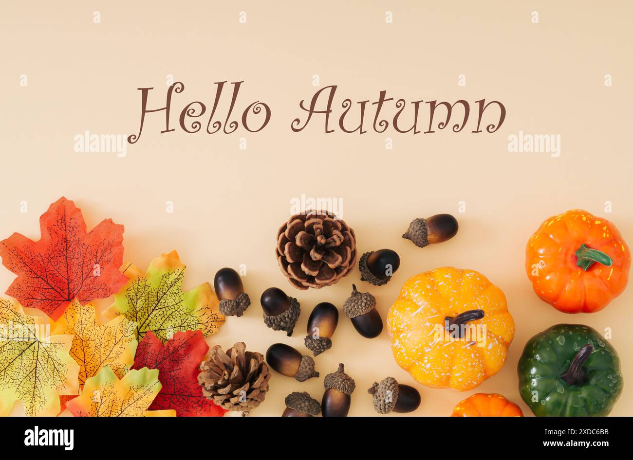 Scène d'automne ou d'automne faite avec des feuilles d'automne colorées, diverses citrouilles, pommes de pin et noix avec texte Hello Autumn sur fond beige pastel. Banque D'Images