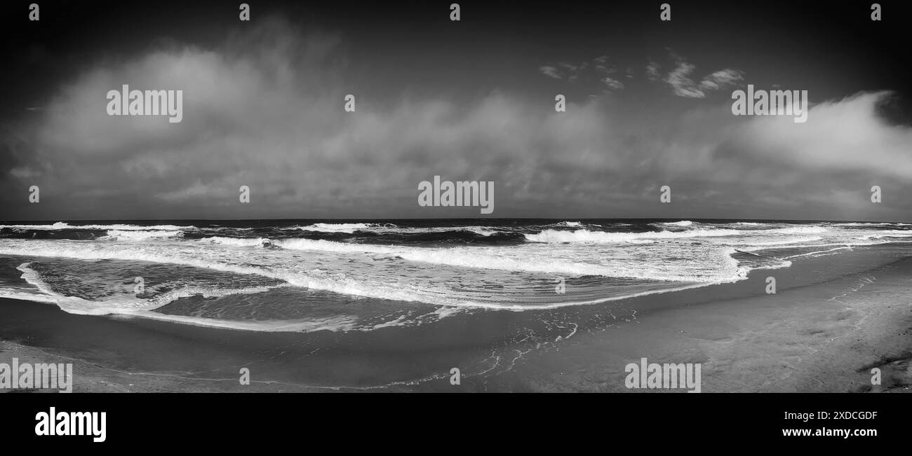 Image en noir et blanc capturant une vue panoramique de la côte de l'océan Atlantique un jour d'été. Whitecaps cramponnent les vagues bleues alors qu'elles s'écrasent contre Banque D'Images