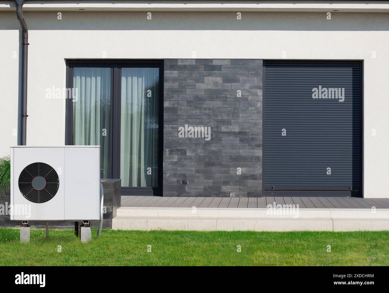 Unité de pompe à chaleur extérieure installée à côté d'une maison moderne avec revêtement en pierre sombre. Banque D'Images