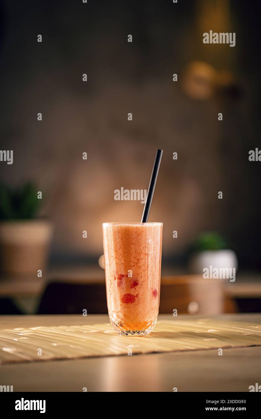 Un smoothie rafraîchissant et sain à base de baies rouges et d'une paille est placé sur une table dans un café Banque D'Images
