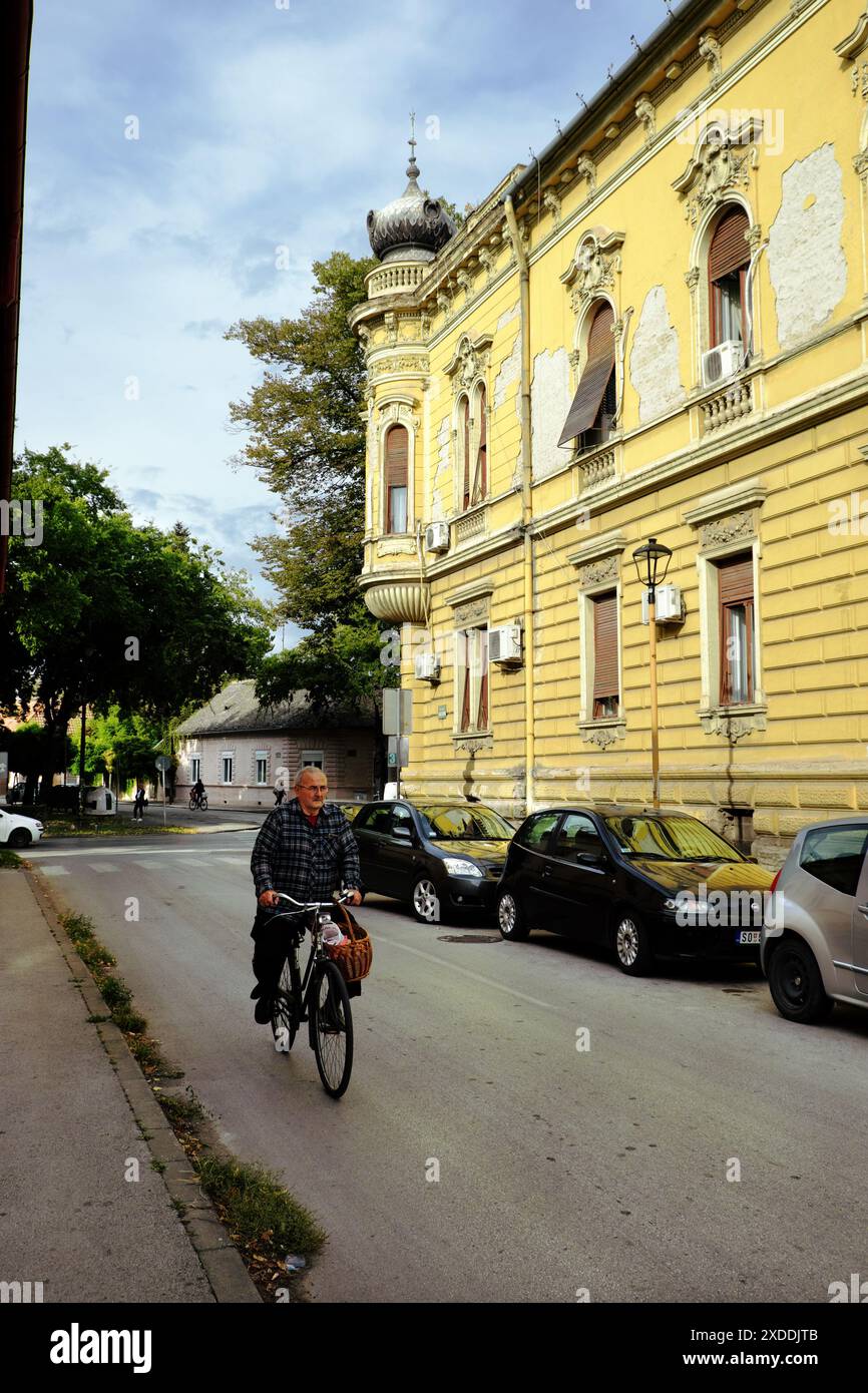 Homme à vélo le long de la rue du Palais Kronic à Sombor, Voïvodine, Serbie Banque D'Images