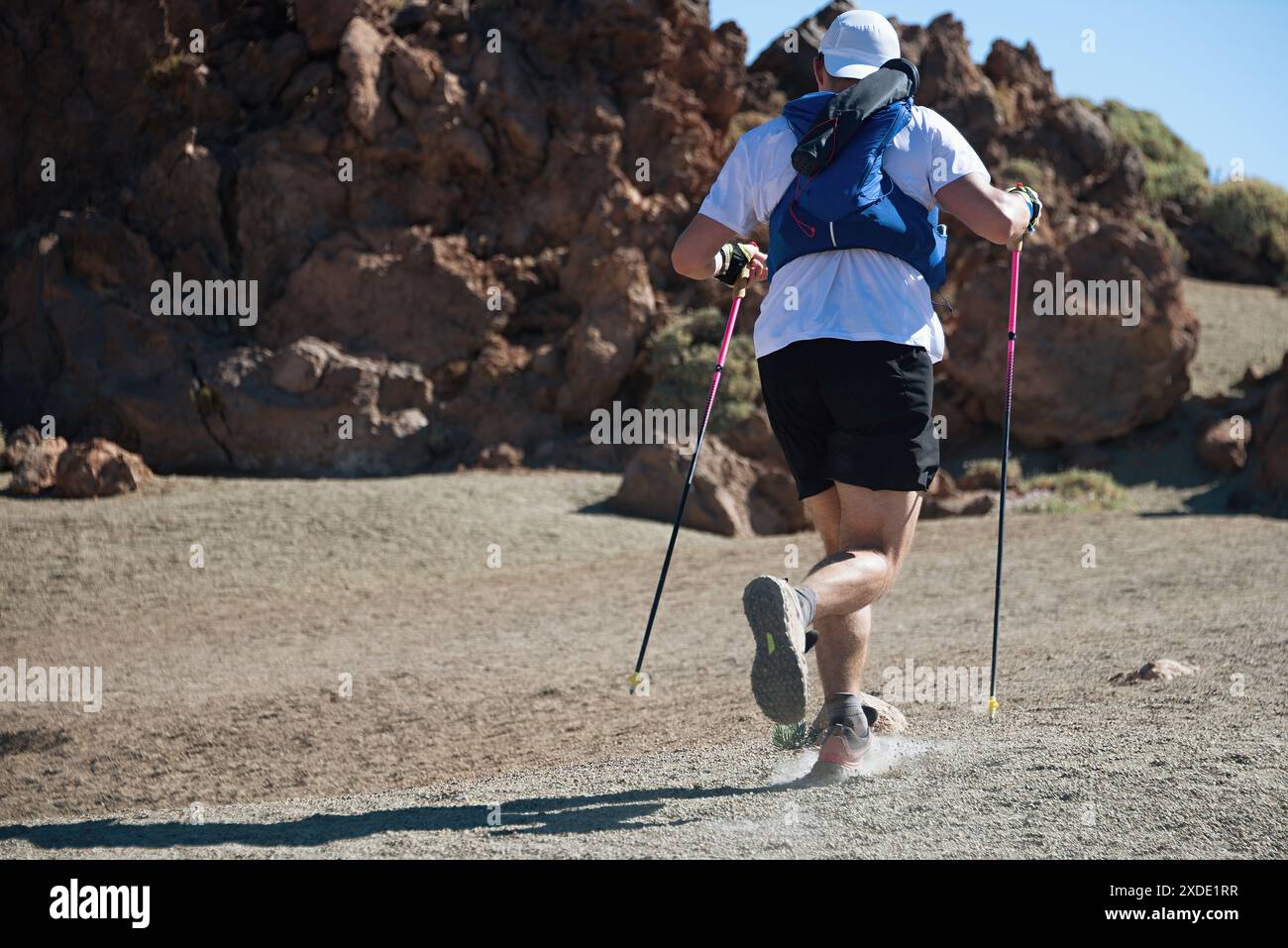 Coureur de trail running homme sur la course d'endurance avec gilet de trail hydratation sur la montagne du volcan. Athlète de course ultra marathon sur le chemin des roches volcaniques Banque D'Images