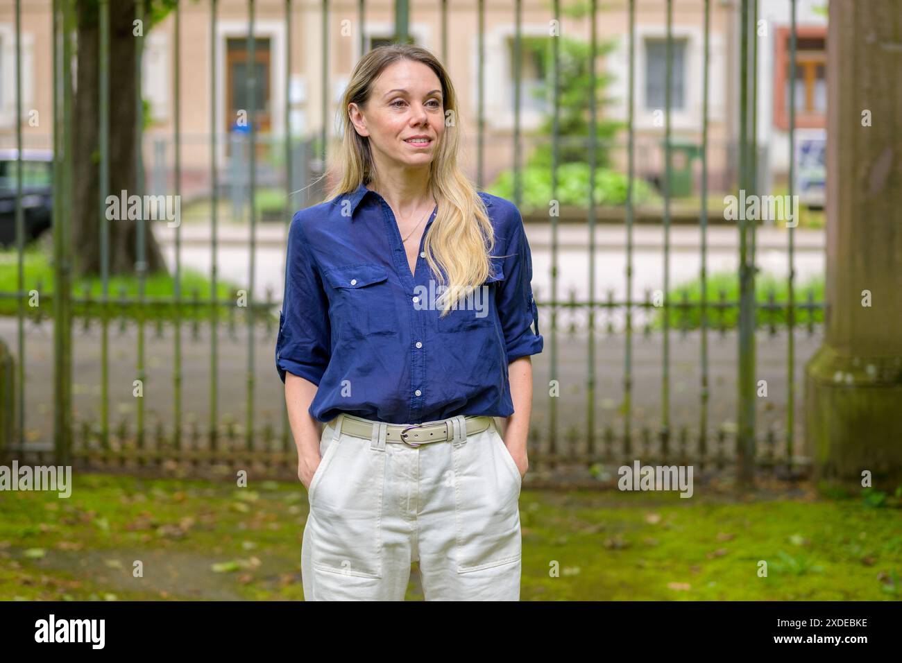 Une femme portant une chemise bleue et un pantalon blanc apprécie une promenade en plein air. Banque D'Images