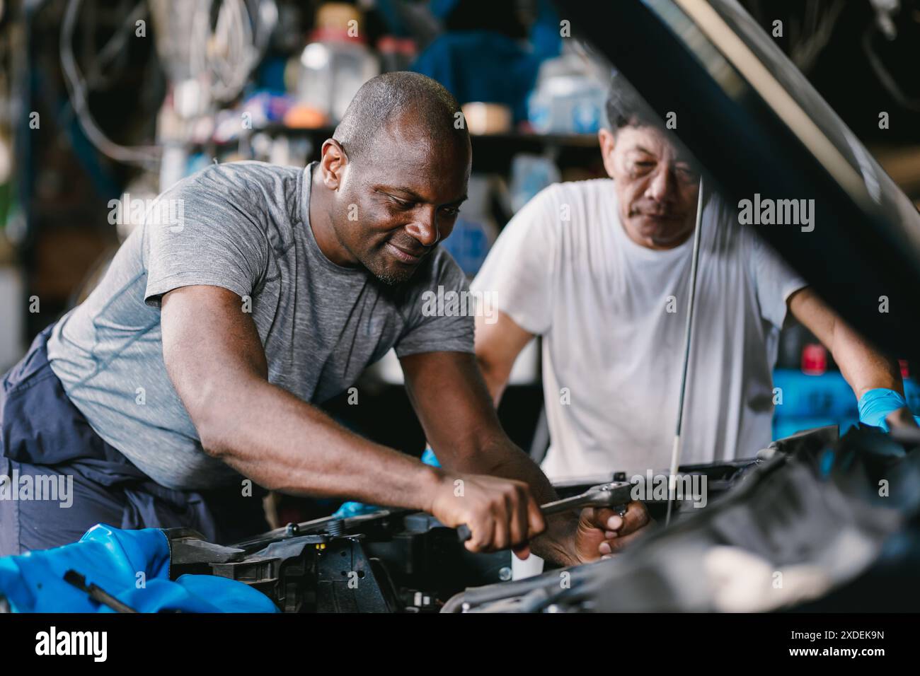 Les hommes de l'équipe de mécanicien travaillant ensemble pour réparer le problème de moteur dans l'atelier d'auto de voiture Banque D'Images