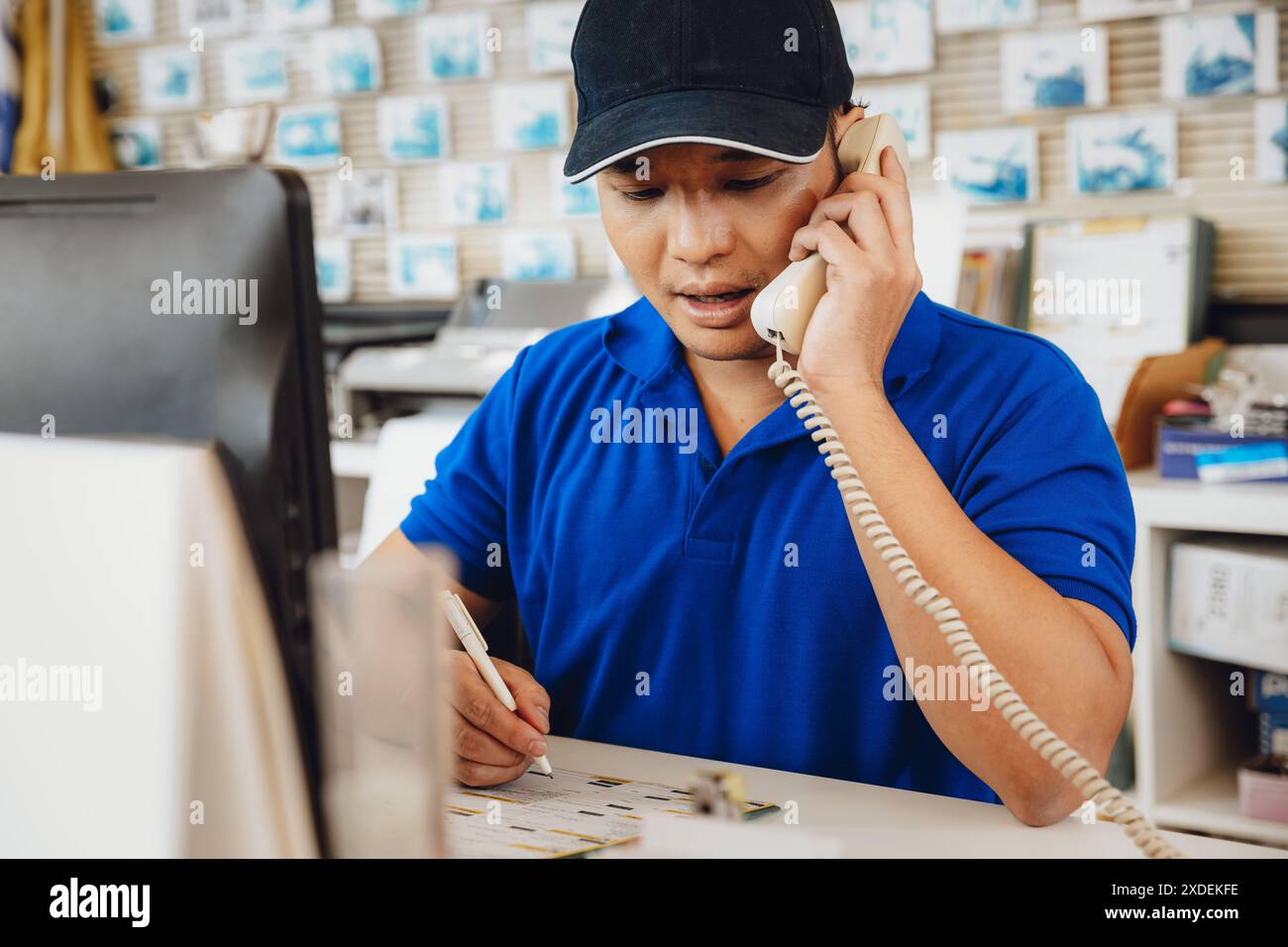 un vendeur recevant un appel téléphonique travaillant à l'aide de bureau soutient le service à la clientèle dans l'atelier de garage automobile de voiture. Banque D'Images