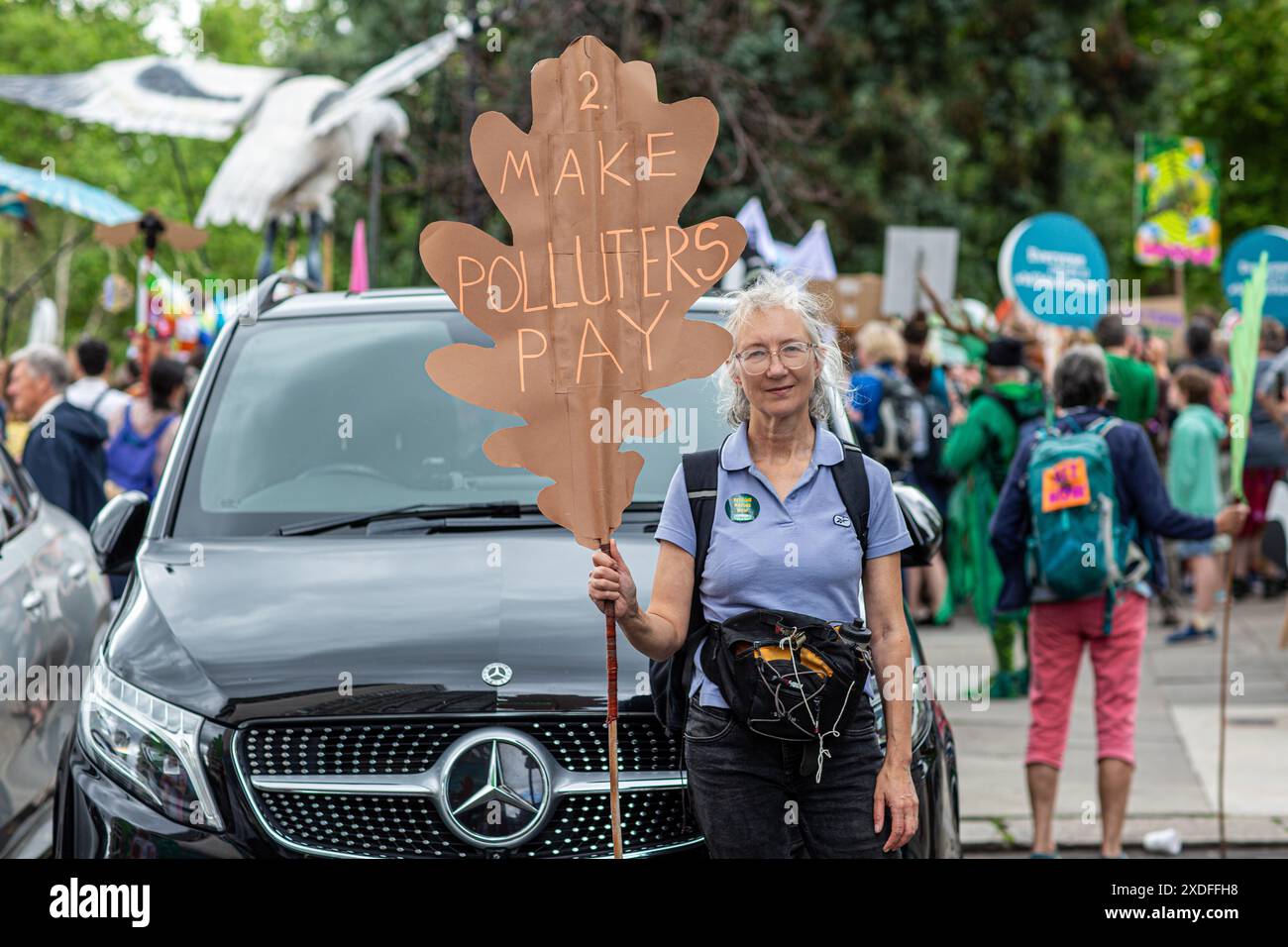 Une femme tient une pancarte faire payer les pollueurs devant une voiture de luxe suv à Londres , Royaume-Uni . Banque D'Images