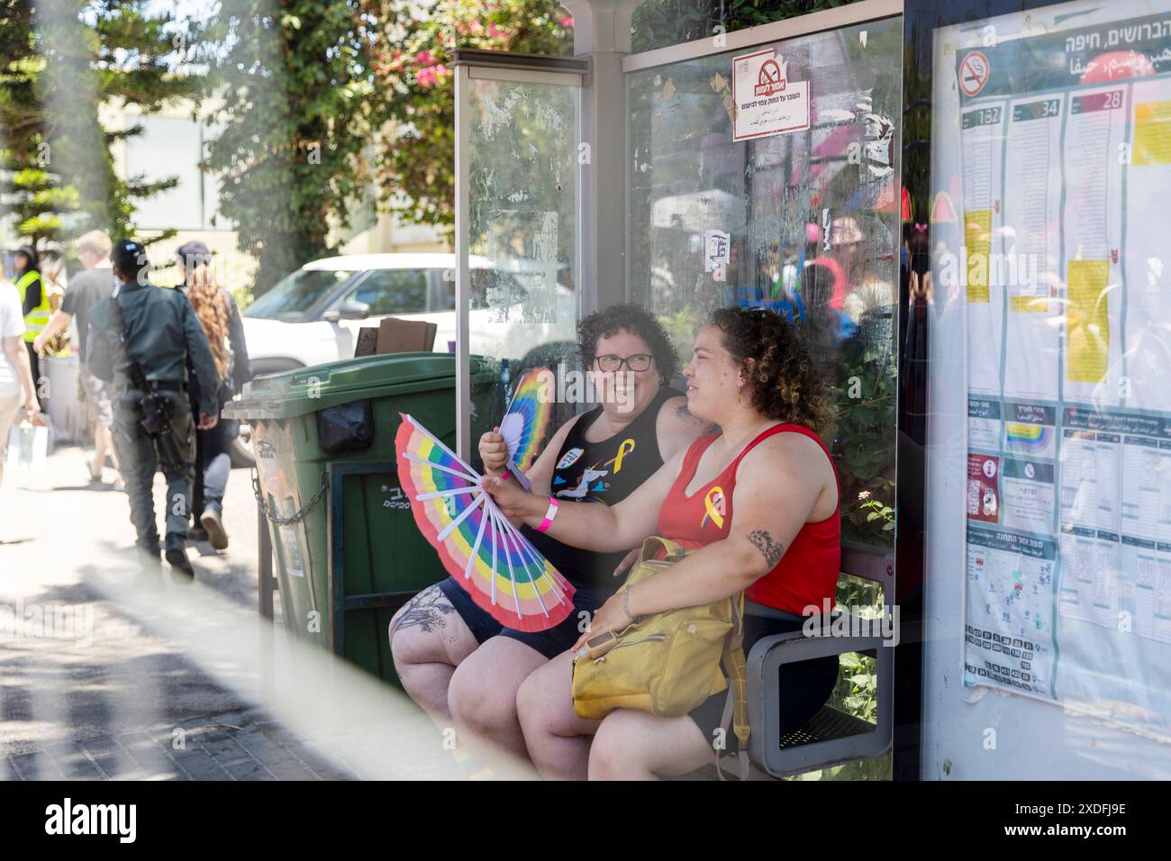 Haïfa, Israël 21 juin 2024, fierté. Les gens avec du maquillage et des drapeaux arc-en-ciel sont assis à l'arrêt de bus. Banque D'Images