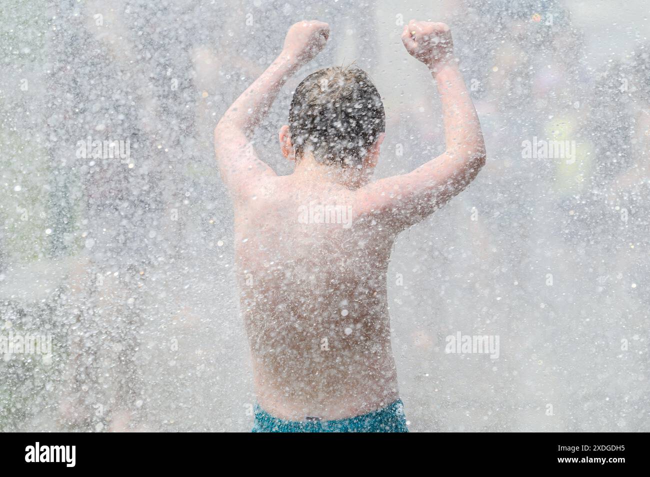 Les enfants gambadent dans le jet d'une bouche d'incendie ouverte par la barre, VT, USA, service d'incendie pendant une vague de chaleur. Banque D'Images