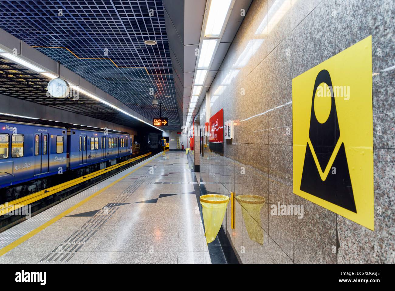 Téhéran, Iran - 18 octobre 2018 : train bleu sur la station de métro Tajrish. Le panneau de wagon de train réservé aux femmes sur le mur est visible à droite. Banque D'Images