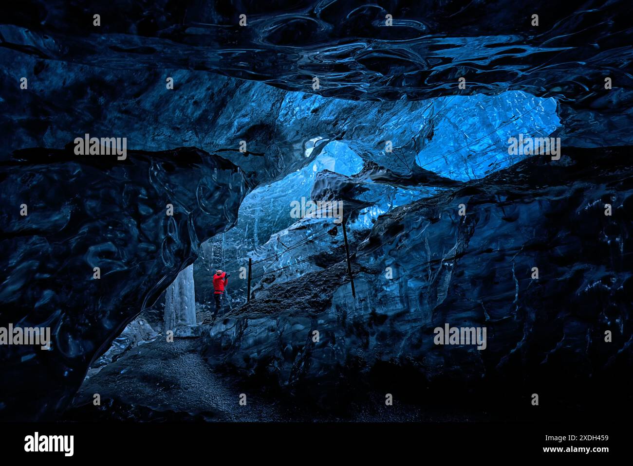 Personne dans une veste rouge à l'intérieur d'une grotte de glace glaciaire, Islande. Banque D'Images