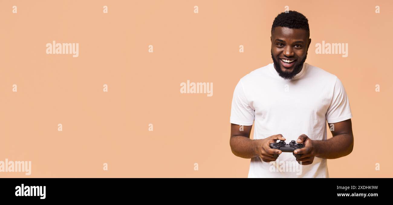 Joyeux homme noir jouant à des jeux vidéo avec contrôleur Banque D'Images