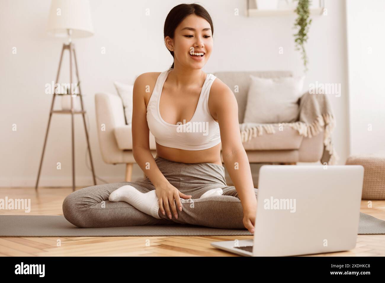 Femme pratiquant le yoga à la maison avec ordinateur portable Banque D'Images