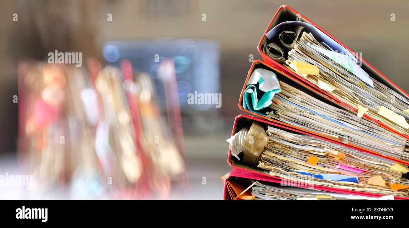 dossiers de fichiers désordonnés et dossiers d'affaires, bureaucratie, bureaucratie, surchargé de travail, battre le concept d'affaires d'horloge sur fond de bureau flou. Banque D'Images