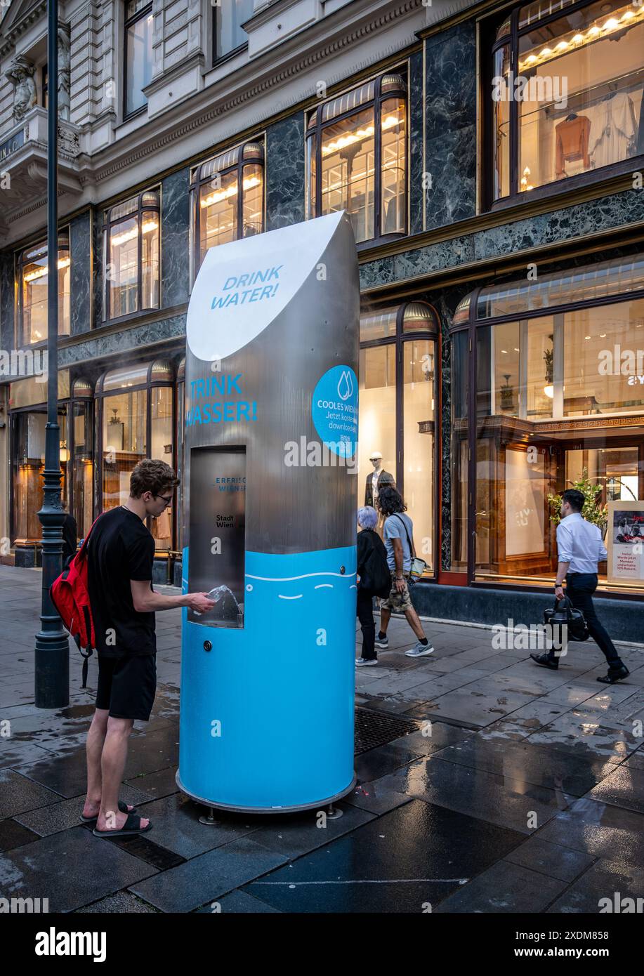 Vienne, Autriche, 18 août 2022. Un distributeur d'eau potable dans une rue de la vieille ville, un garçon remplit sa bouteille d'eau. Sur le côté, les signes Banque D'Images