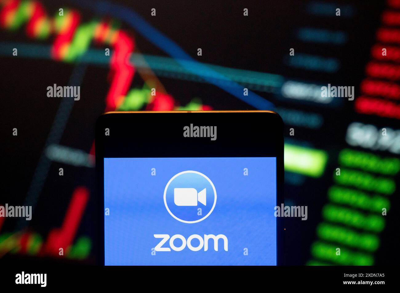 Dans cette illustration photo, le logo de la société américaine de communication vidéo Zoom (NASDAQ : ZM) vu affiché sur un smartphone avec un graphique d'indice boursier économique en arrière-plan. Banque D'Images