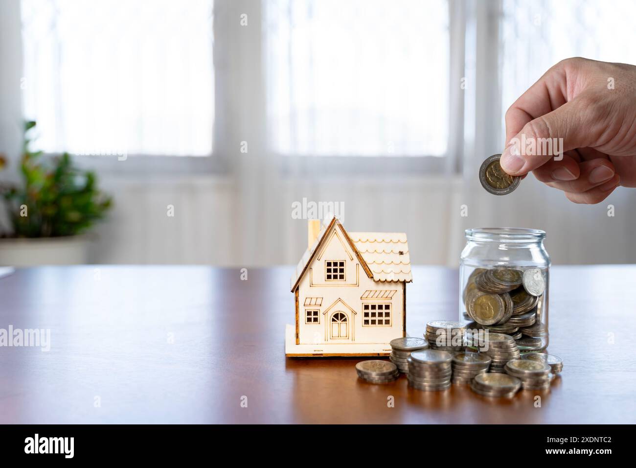 Fermez homme d'affaires tenant des pièces de monnaie mettant dans la tirelire et écrivez ou prenez note dans le livre et les pièces de monnaie devant. Économiser de l'argent pour la comptabilité de financement de plan Banque D'Images