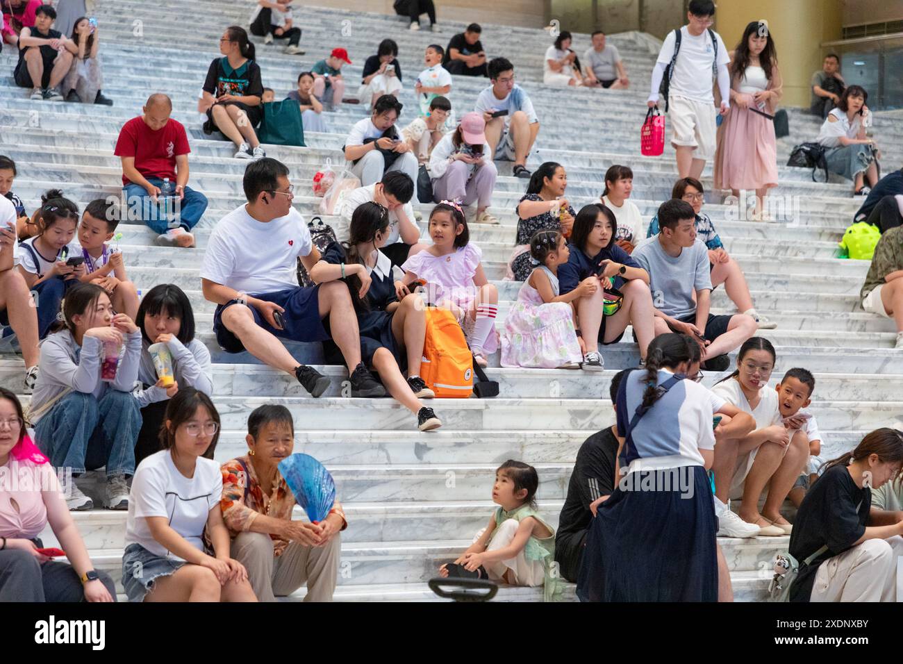 JINAN, CHINE - 23 JUIN 2024 - les gens sont assis sur les marches de la salle du musée du Shandong pour se rafraîchir dans la province du Shandong, province du Shandong en Chine orientale Banque D'Images