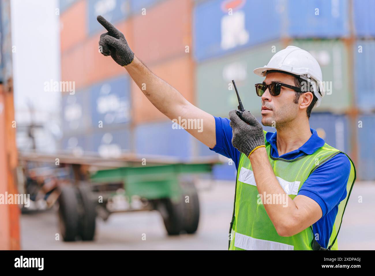 Hispanique homme ouvrier maritime de fret portuaire travaillant le contrôle radio opèrent dans la cour de conteneurs douaniers d'expédition de fret portuaire. Banque D'Images