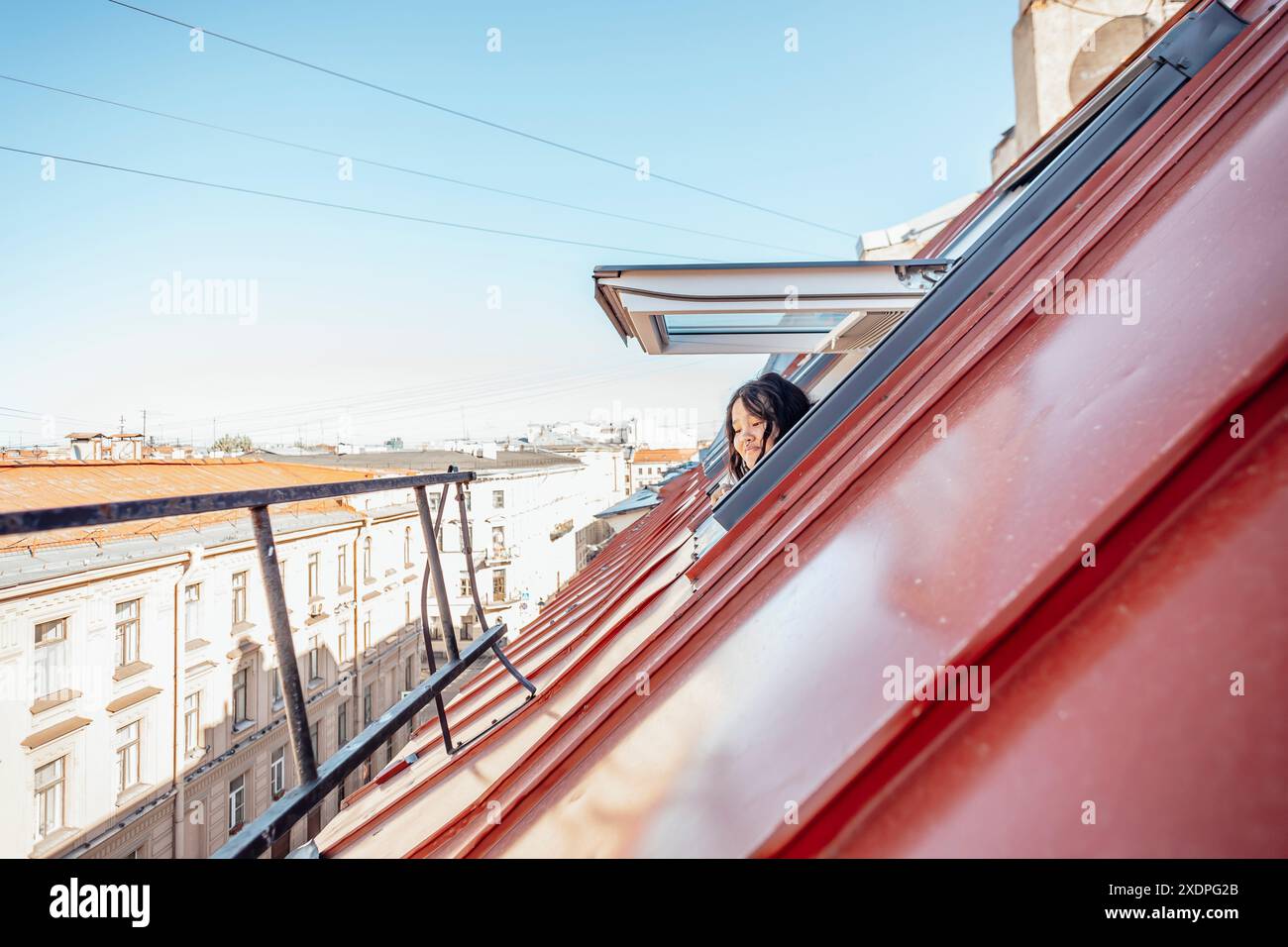 évasion, perspective comme la femme regarde par la fenêtre du grenier sur le paysage urbain Banque D'Images