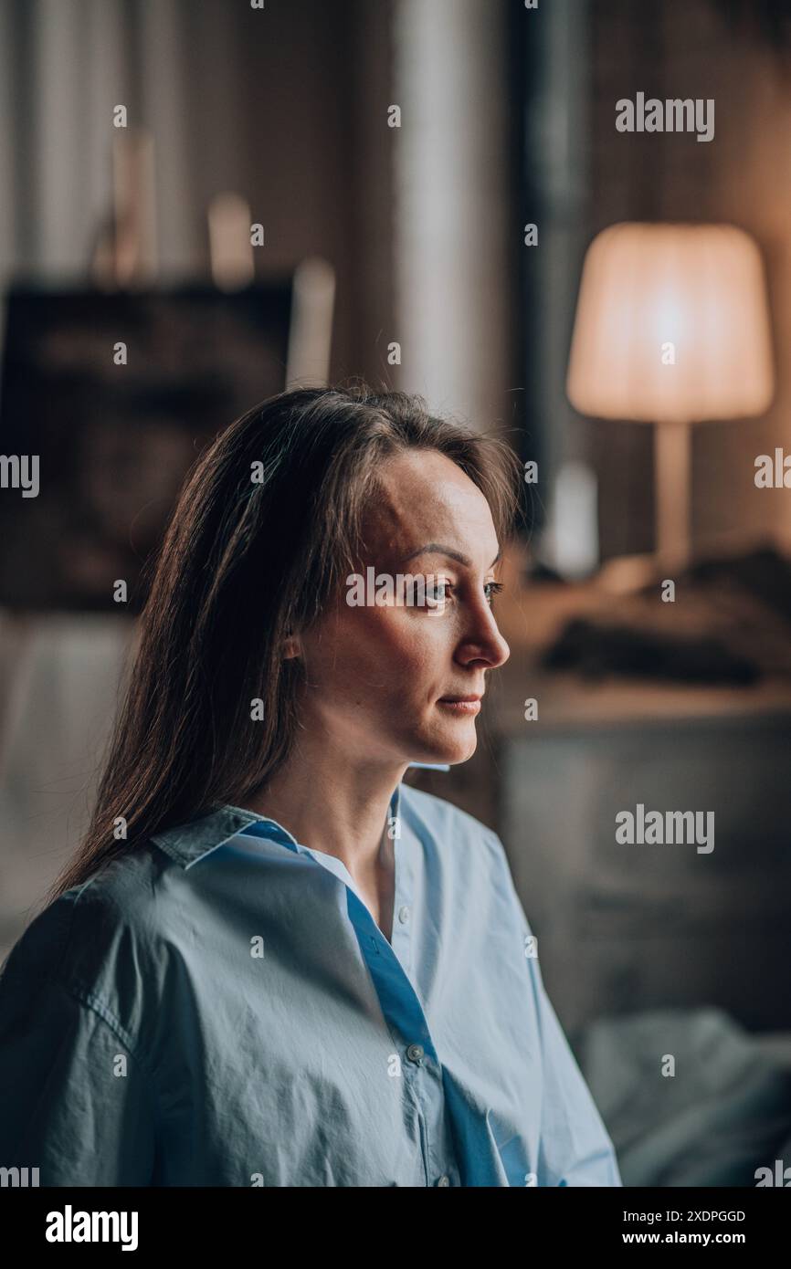 Réflexions pensives. Dans la lueur douce de la lampe, la femme réfléchit profondément Banque D'Images